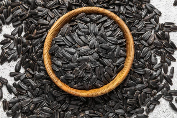 Bowl of black sunflower seeds on light background