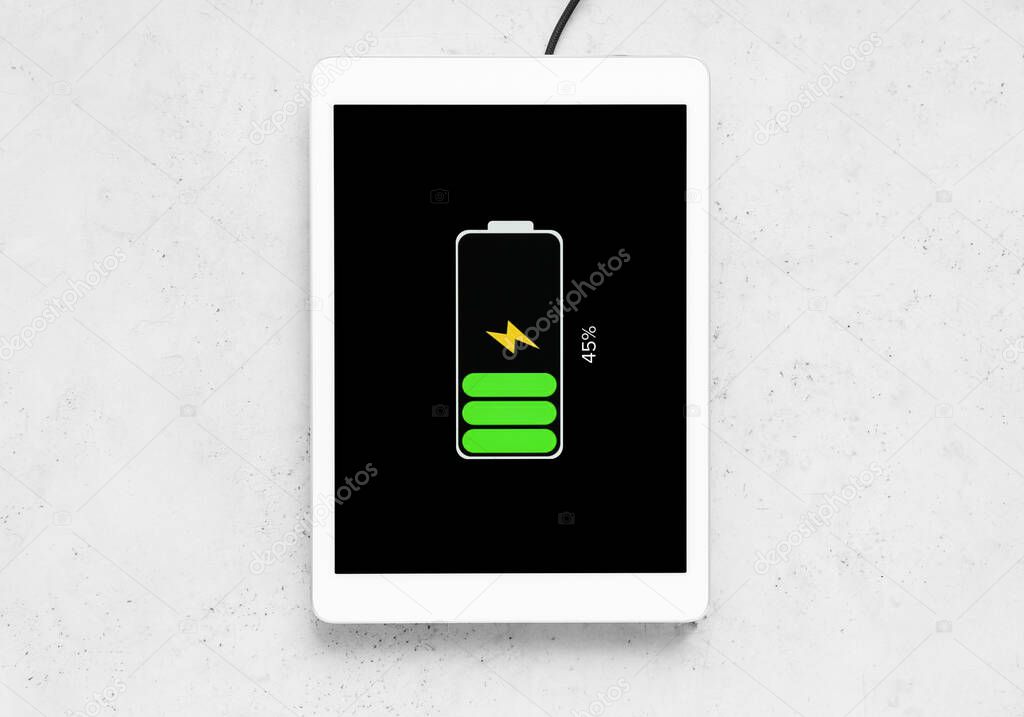 Tablet computer charging with wireless pad on grunge background