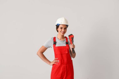 Arka planda boru anahtarı olan kadın tesisatçı.