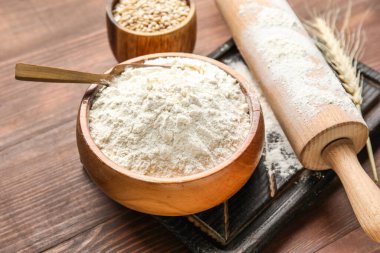 Buğday kulağı, un dolu kâseler, tahta arka planda merdane ve tahta, yakın plan.