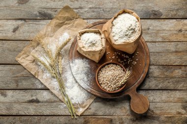 Tahta arka planda buğday kulakları, kase, un, tahta ve parşömen kağıtları.