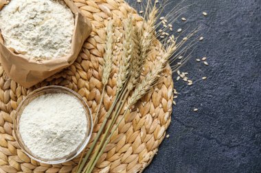 Hasır, buğday kulağı, kese kağıdı ve koyu arkaplanda un.