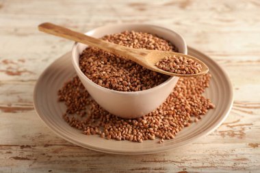 Tabaklar ve kaşık hafif ahşap zemin üzerinde karabuğday taneleri