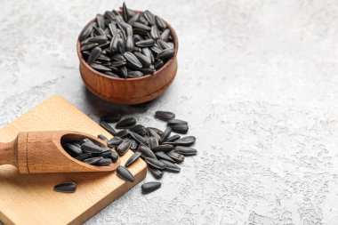 Kase, yemek ve kepçeyle açık arkaplanda siyah ayçiçeği tohumları