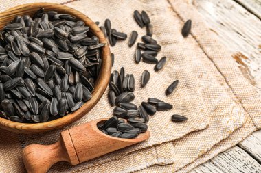 Kase, kepçe ve peçeteyle beyaz ahşap arka planda ayçiçeği tohumları