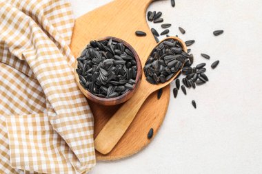 Beyaz zemin üzerinde kâse, kaşık ve ayçiçeği tohumları olan tahta