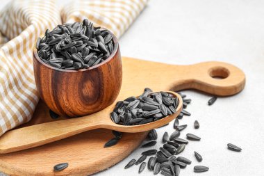 Beyaz zemin üzerinde kâse, kaşık ve ayçiçeği tohumları olan tahta