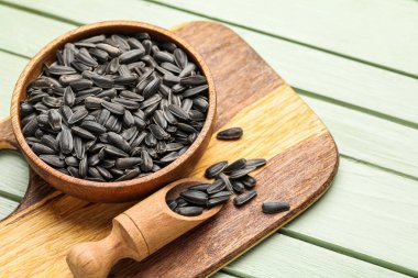 Yeşil arka planda kase, kepçe ve ayçekirdeği olan tahta