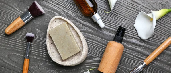 Koyu ahşap arka planda kozmetik ürünler ve makyaj fırçaları.
