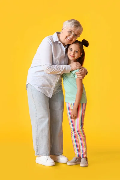 Κοριτσάκι Και Γιαγιά Της Αγκαλιάζονται Κίτρινο Φόντο — Φωτογραφία Αρχείου
