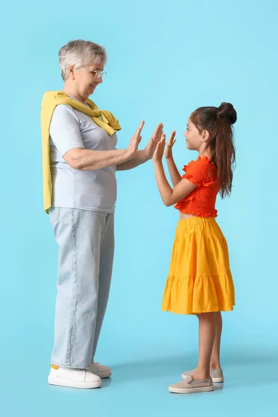 Little Girl Giving High Five Her Grandma Blue Background — Stock Photo, Image