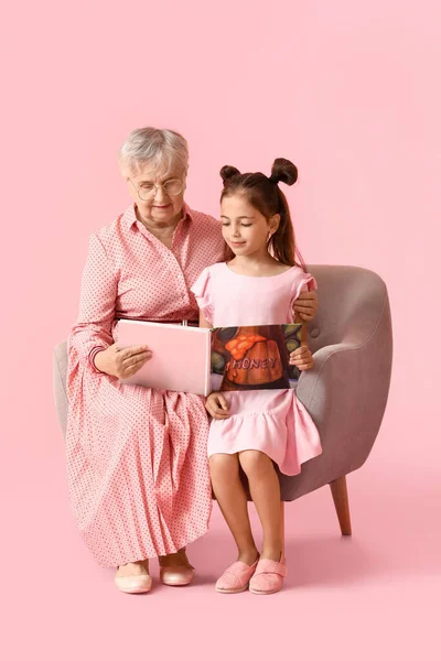 Senior Woman Her Little Granddaughter Reading Book Armchair Pink Background — Stock Photo, Image