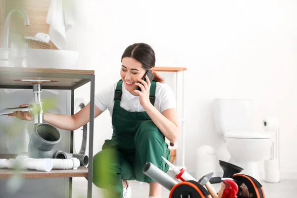 Asiatische Klempnerin Telefoniert Mit Handy Während Sie Waschbecken Badezimmer Repariert — Stockfoto