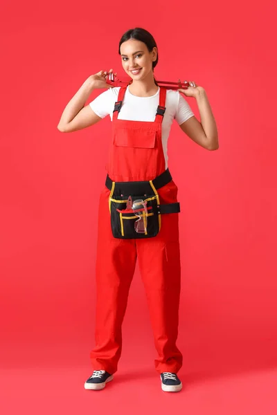 赤い背景にパイプレンチを持つ女性配管工 — ストック写真