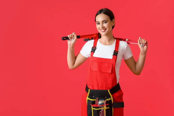 Vrouwelijke Loodgieter Met Pijpsleutels Rode Achtergrond — Stockfoto