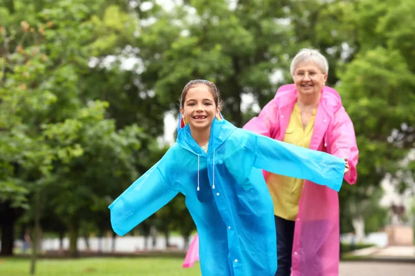 Yağmurluklu Küçük Kız Büyükannesiyle Dışarıda Eğleniyor — Stok fotoğraf