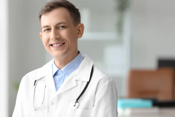 Male medical assistant with stethoscope smiling in clinic