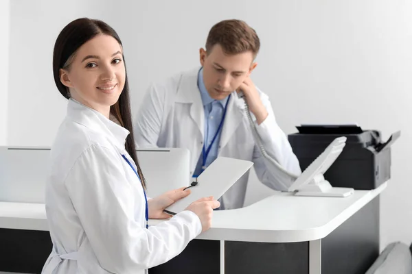 Médica Com Pasta Perto Recepcionista Clínica — Fotografia de Stock