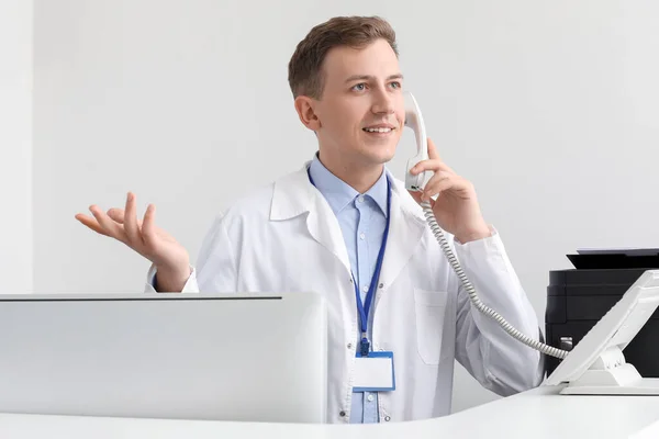 Αντρας Ρεσεψιονίστ Μιλάει Τηλεφωνικώς Στο Γραφείο Στην Κλινική — Φωτογραφία Αρχείου