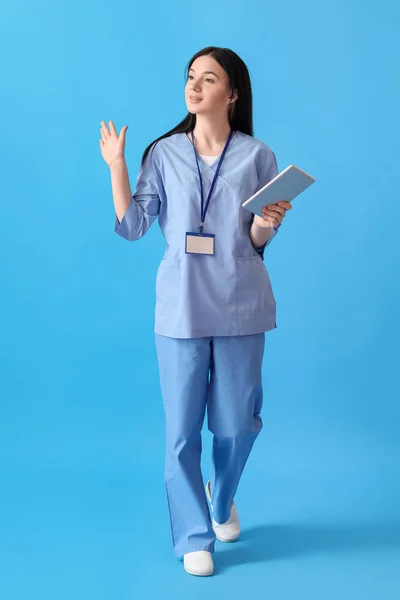 青の背景に手を振ってタブレットコンピュータと女性医療アシスタント — ストック写真