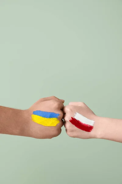 Волонтеры Нарисованными Флагами Украины Польши Бьют Кулаками Зеленом Фоне — стоковое фото