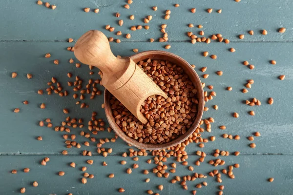 Kap ve kepçe ile karabuğday taneleri renkli ahşap masa üzerinde