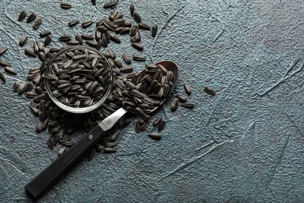 Koyu arkaplanda ayçiçeği tohumları olan kase ve kaşık
