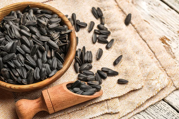 Kase, kepçe ve peçeteyle beyaz ahşap arka planda ayçiçeği tohumları