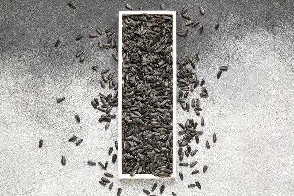 Siyah ve beyaz arkaplanda ayçiçeği tohumları olan tahta