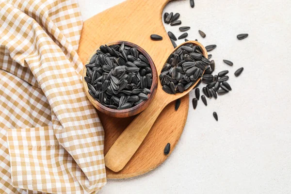 Beyaz zemin üzerinde kâse, kaşık ve ayçiçeği tohumları olan tahta