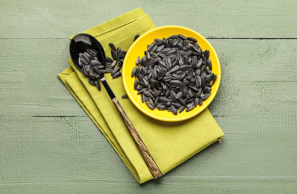 Siyah ayçiçeği tohumları, yeşil ahşap arka planda kaşık ve peçete.