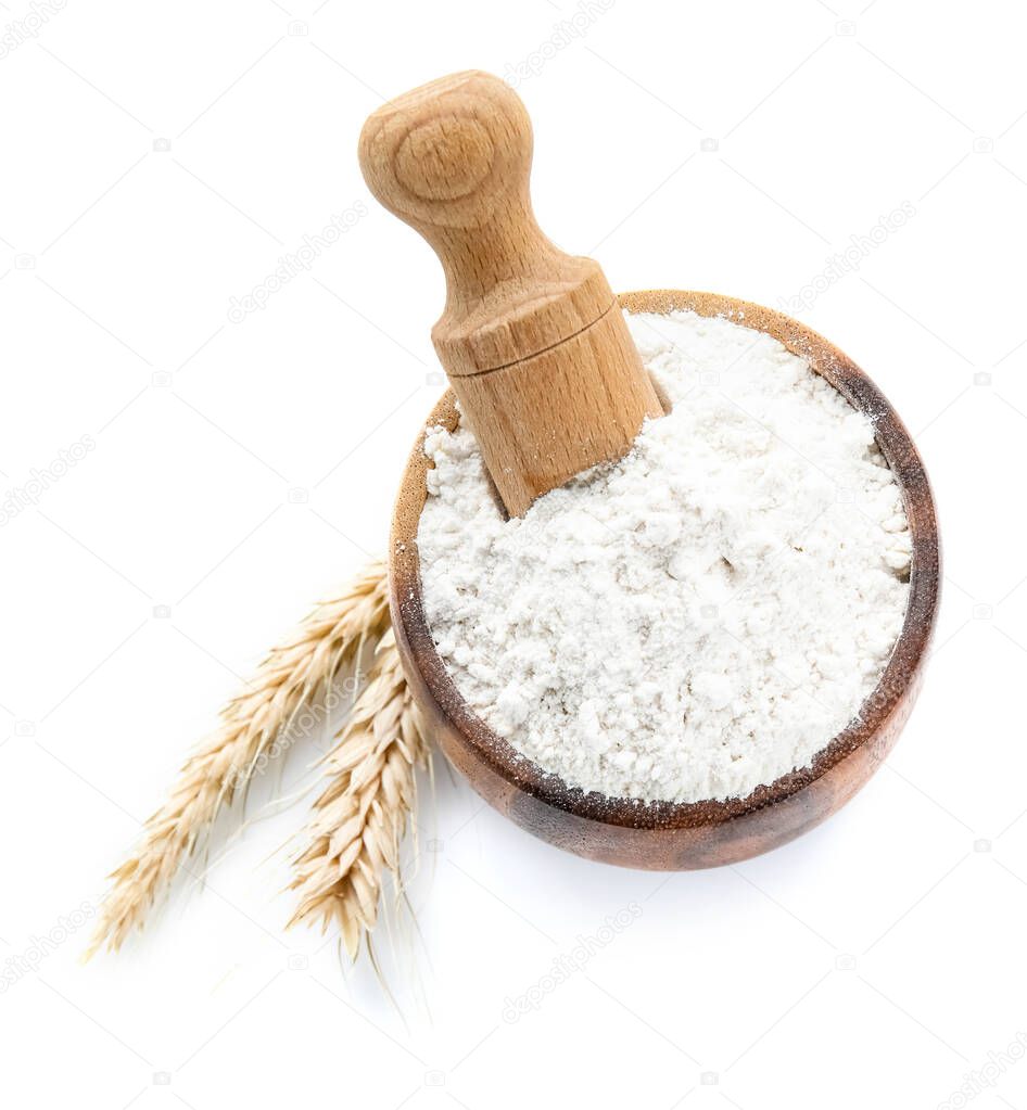 Bowl with flour, scoop and wheat ears on white background