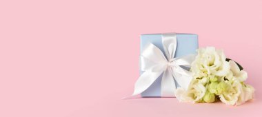Hediye kutusu ve çiçek buketi pembe arka planda ve metin için yeri var.