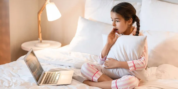 Surprised girl watching cartoons in bedroom