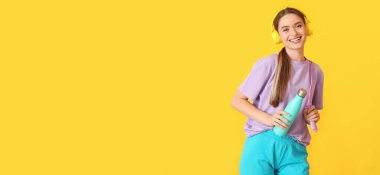 Bir şişe su ve ip atlama ile sportif genç kadın sarı arka planda müzik dinlerken metin için yer var.