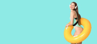 Şişme yüzüklü, açık mavi arka planda müzik dinleyen, metin için yeri olan mutlu genç bir kadın.