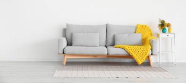 Işık duvarının yanında mimoza çiçekli kanepe ve masa.