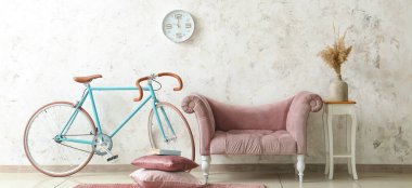 Pembe kanepe, masa ve bisikletle aydınlık oturma odasının içinde.