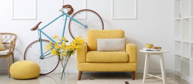 Bisikletli, sarı koltuklu, masa ve raf üniteli modern bir oda.