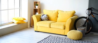 Sarı kanepe ve bisiklet şık oturma odasının içinde.