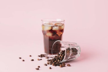 Soğuk bira bardakları ve pembe arka planda kahve çekirdekleri.