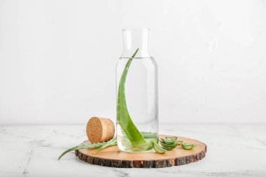 Cam şişe aloe suyu ve beyaz arka planda yaprakları olan tahta.