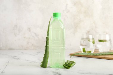 Bir şişe aloe suyu ve açık arkaplanda yapraklar