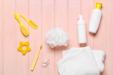 Pembe tahta arka planda bebek için farklı banyo aksesuarları.