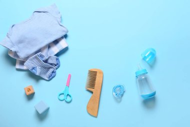 Mavi arka planda erkek bebek için kıyafetler ve farklı aksesuarlar.