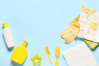 Güzel bebek kıyafetleri ve mavi arka planda banyo aksesuarları.