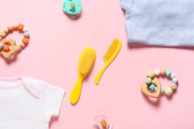 Pembe arka planda şirin bebek kıyafetleri ve aksesuarlar, yakın plan.