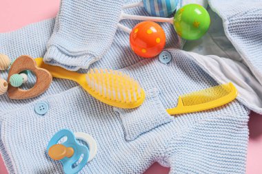 Bebek için örülmüş süveter ve pembe arka planda farklı aksesuarlar, yakın plan.