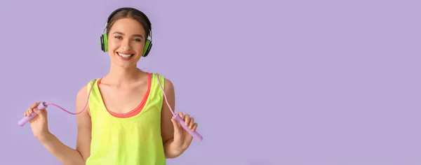 Sportliche Junge Frau Mit Springseil Hört Musik Auf Fliederfarbenem Hintergrund — Stockfoto