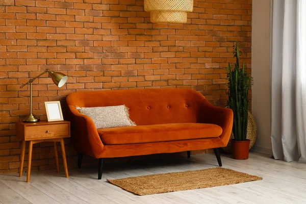 レンガの壁の近くにソファとテーブル付きのスタイリッシュなリビングルームのインテリア — ストック写真